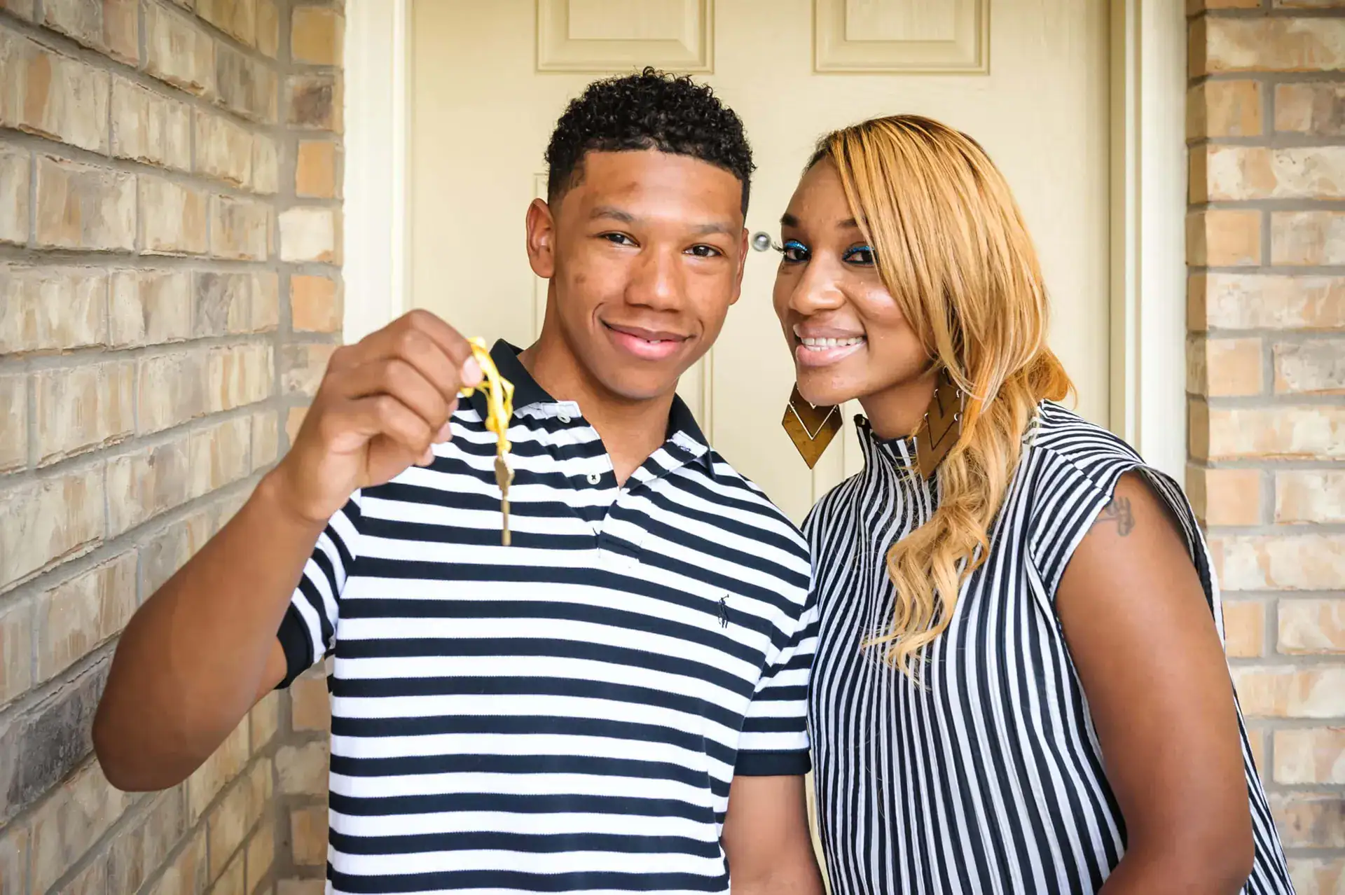 First-time home buyers in Dallas holding keys to their new home.